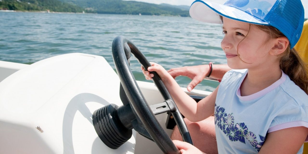 Little girl driving motorboat Lake Winnipesaukee attractions
